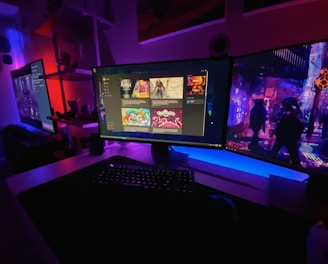 A gaming setup featuring multiple screens with vibrant game-related images illuminated by colorful LED lighting. The environment is dimly lit, highlighting the vivid displays on the monitors. A keyboard is visible on the desk beneath the central monitor.
